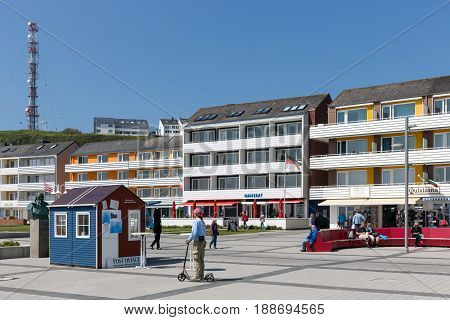 HELGOLAND GERMANY - MAY 27 2017: Relaxing people and houses of the village along the harbor at Helgoland