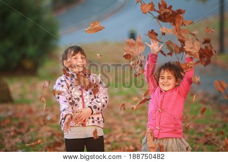 outdoor portrait of two young happy children, girls - sisters - playing in park on natural background 