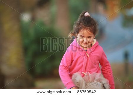outdoor portrait of young happy child girl playing in park on natural background
