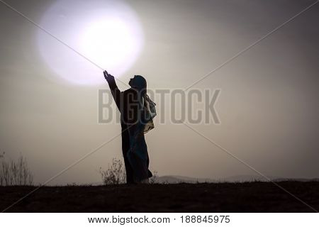 Silhouette woman praying with her hands up