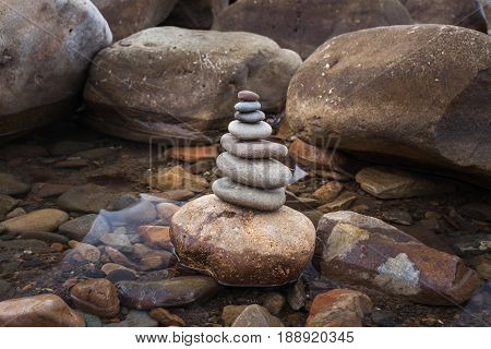 Pyramid Of Stones On A Background Sea Of Large Stones And Water