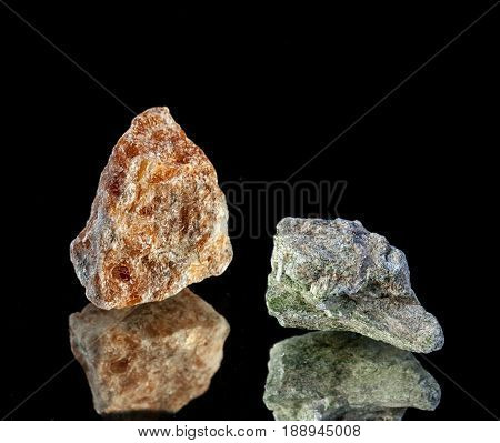 Orange calcite and chrome diopside on a black background close-up and reflection