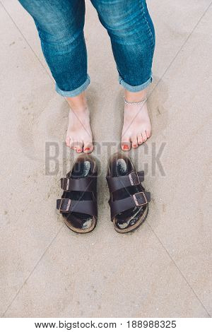 Barefoot girl on the beach next to her shoes