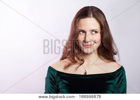 Portrait of thinkful woman with freckles and classic green dress. studio shot on silver gray background.
