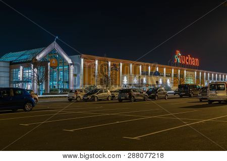 Roncq,france-february 27,2019: Night View Of Auchan Supermarket Logo, Entrance And Parking.auchan Is