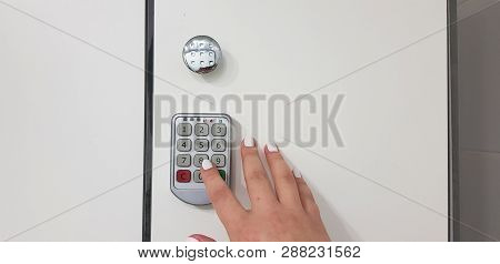 Female Hand Presses A Number Key On Electric Security Lock On White Locker Closed Door