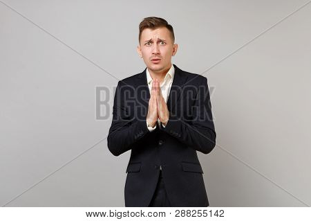 Pleading Young Business Man In Classic Black Suit And Shirt Holding Hands Together, Praying Isolated