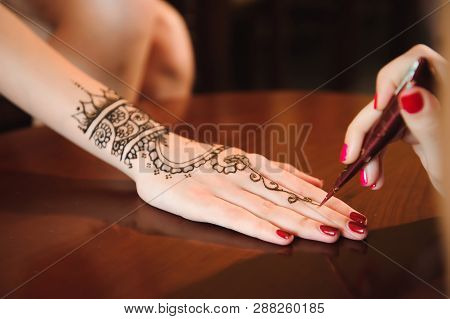 Master Mehndi Draws Henna On A Female Hand.
