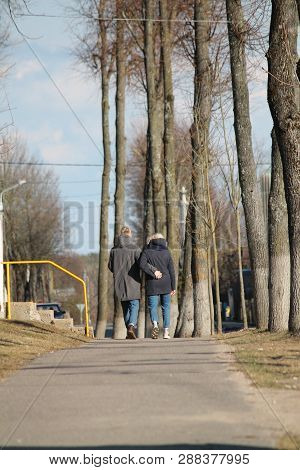 Pair Of Young People Walk Hug On Spring Alley In City Park