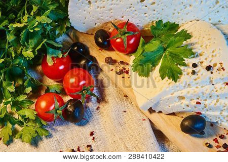 Homemade Georgian Imeretian Cheese On A Wooden Board, Cherry Tomatoes, Walnuts, Grapes, Spices