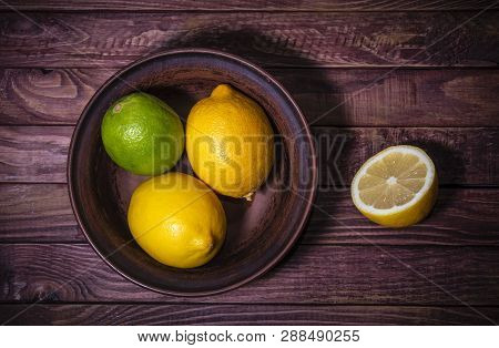 Fresh Lemons In Clay Plate On Wooden Background