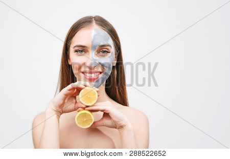 Beautiful Young Woman With Facial Mask And Slice Of Ripe Lemon On Grey Background