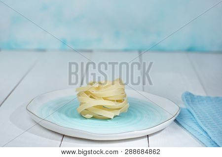Blue Plate With A Nest Of Dry Unpaired Tagliatelle, Cooking Ingredients
