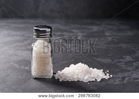 Pile Of Salt And Salt Shaker On Black Stone Background. Vertical Composition.