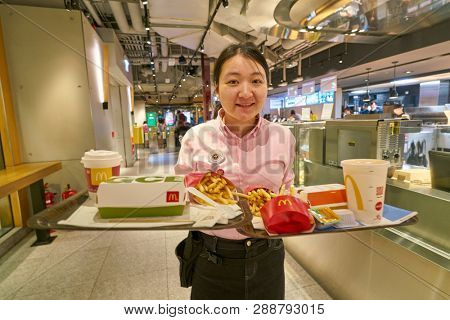 HONG KONG, CHINA - CIRCA FEBRUARY, 2019: indoor portrait of woman with two trays in McDonald's restaurant in Hong Kong. 