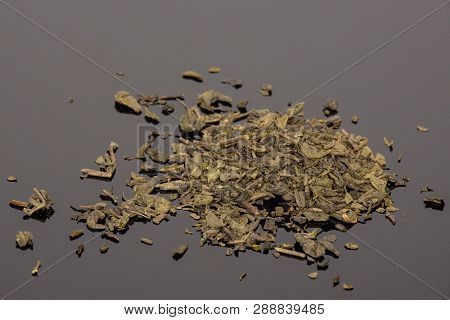 Lot Of Pieces Of Dry Green Tea On Black Glass