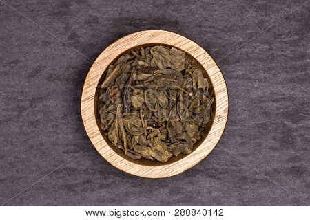Lot Of Pieces Of Dry Green Tea With Wooden Bowl Flatlay On Grey Stone