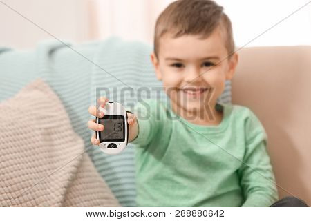 Little Boy Holding Digital Glucose Meter At Home, Focus On Hand. Diabetes Control