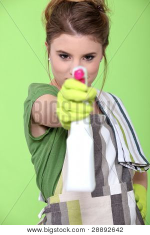 chica sosteniendo el detergente con pistola bomba sobre fondo verde