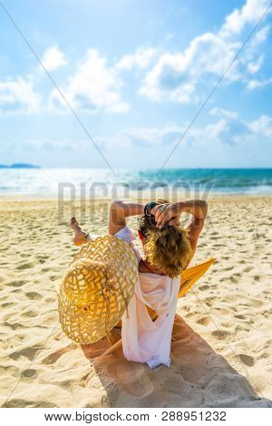 Woman with straw hat enjoying her holidays on a transat at the tropical beach in Thailand