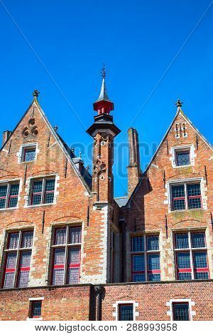 Traditional Medieval Brick House Exterior Against Blue Sky In Belgian Destination Bruges, Belguim