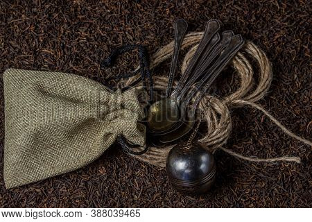 Leaf Tea. A Lot Of Loose Tea. Teaspoons, A Pouch And A Tea Ball Lay On Loose Tea