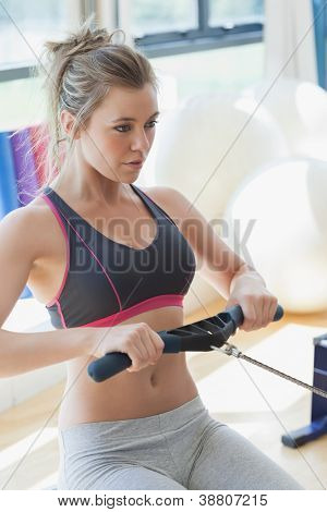 Frau ziehen auf Zeile Maschine im Fitness-studio