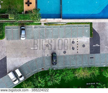 Top View Concrete Car Parking Lot, Swimming Pool, And Garden Of Apartment. Aerial View Of Car Parked