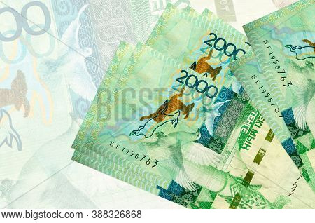 2000 Kazakhstani Tenge Bills Lies In Stack On Background Of Big Semi-transparent Banknote. Abstract 
