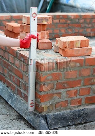 A Mason Person Is Using A Spirit Level To Check If The Surface Of A Brick Foundation Is Even And Lev