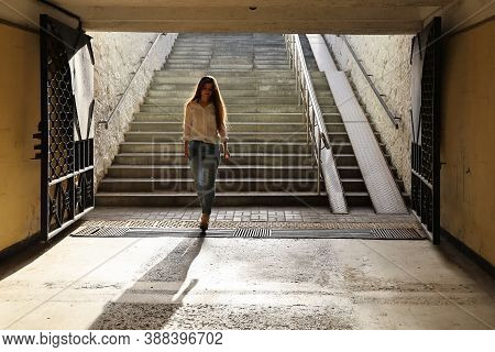 Young Beautiful Woman In Shirt And Jeans Walked Down Into The Pedestrian Underpass. She Smiles And I