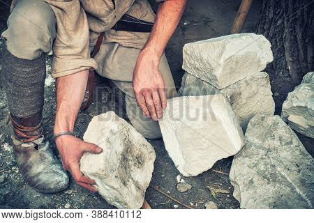 Working In A Quarry Holding Stones. The Mason Chooses A White Limestone Stone For Production., Backg
