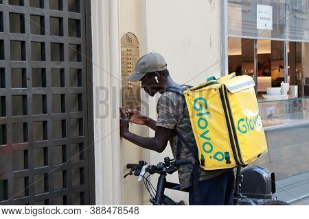 Turin, Italy - September 2020: A Glovo African Courier Rings At The Customers Doorbell For Delivery.