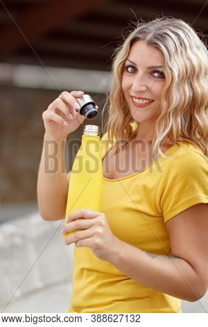 Young Woman In Yellow T-shirt Opening Yellow Reusable Bottle