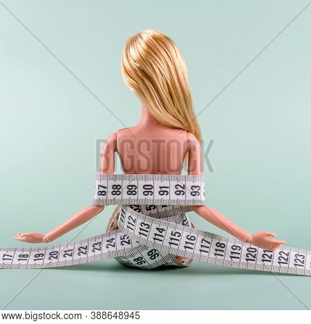 Doll Wrapped In Measuring Tape. Tied Up Unrecognizable Plastic Doll, Weight Loss, Fasting And Slimmi