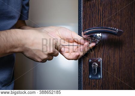 Close-up Of Male Hands Repairing Or Replacing An Entrance Door Lock With A Hex Screwdriver. Increase