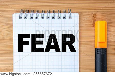 Business Concept. On The Wooden Table Is A Marker And A Notebook With The Inscription Fear First Enc