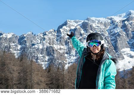 A Woman In A Colorful Ski Suit, Helmet And Sunglasses After Skiing Stands Against The Backdrop Of Mo