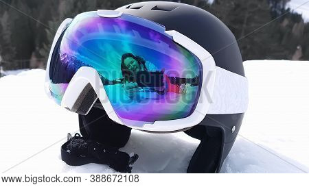 View Of A Ski Helmet With Sunglasses Reflecting A Woman. Landscape, Industry, Sports Concept.
