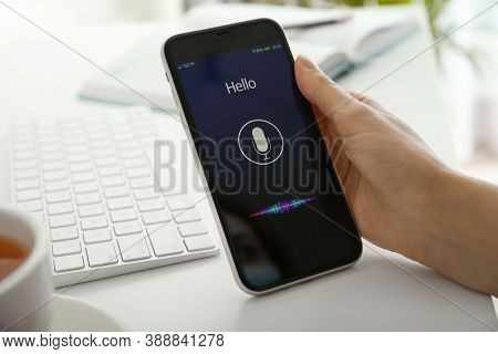 Woman Using Voice Search On Smartphone At White Table, Closeup