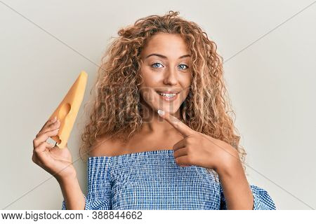 Beautiful caucasian teenager girl holding a piece of emmental cheese smiling happy pointing with hand and finger 