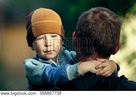Sad little boy in his father's arms.