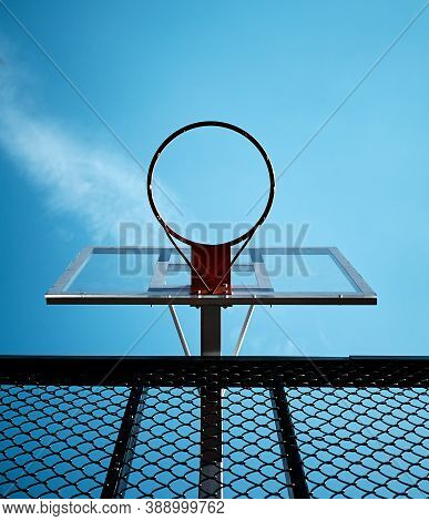 Basketball Ring Near The Netting. Sports Equipment On A Background Of Sunny Blue Sky.