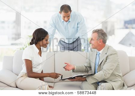 Salesman showing clients where to sign the contract in the office