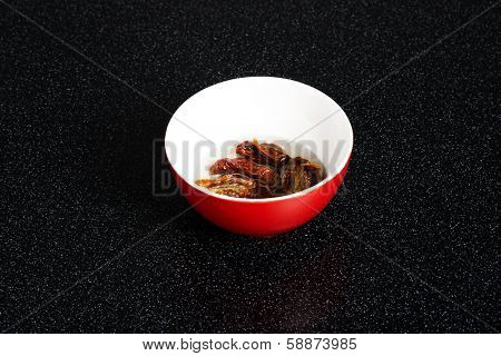 Dry mashroom put in a red bowl with water.