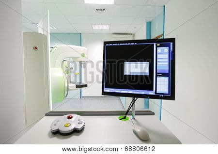 Mammography breast screening device in hospital laboratory with computer display in foreground.