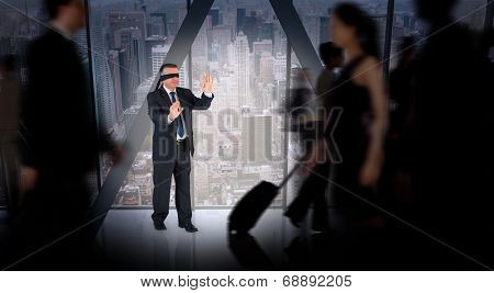 Mature businessman in a blindfold against room with large window looking on city