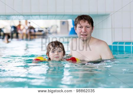Young Dad Teaching His Little Son To Swim Indoors