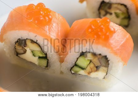 Sushi Rolls With Salmon, Avocado And Cream Cheese, Decorated With Red Caviar, Served On White Slate.