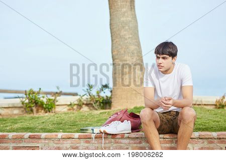 Young Man Waiting On Wall Outside With His Stuff